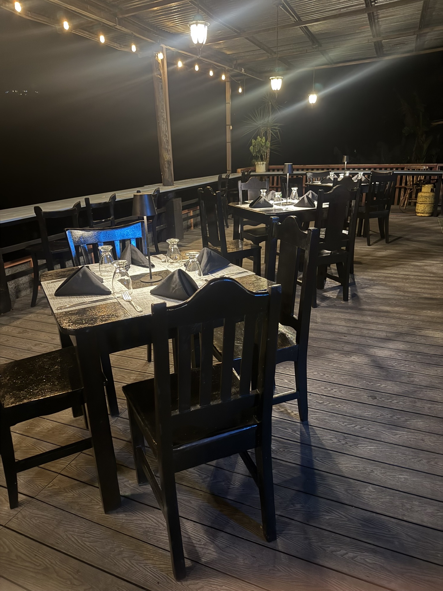 Outdoor deck set for dinner under string lights at night